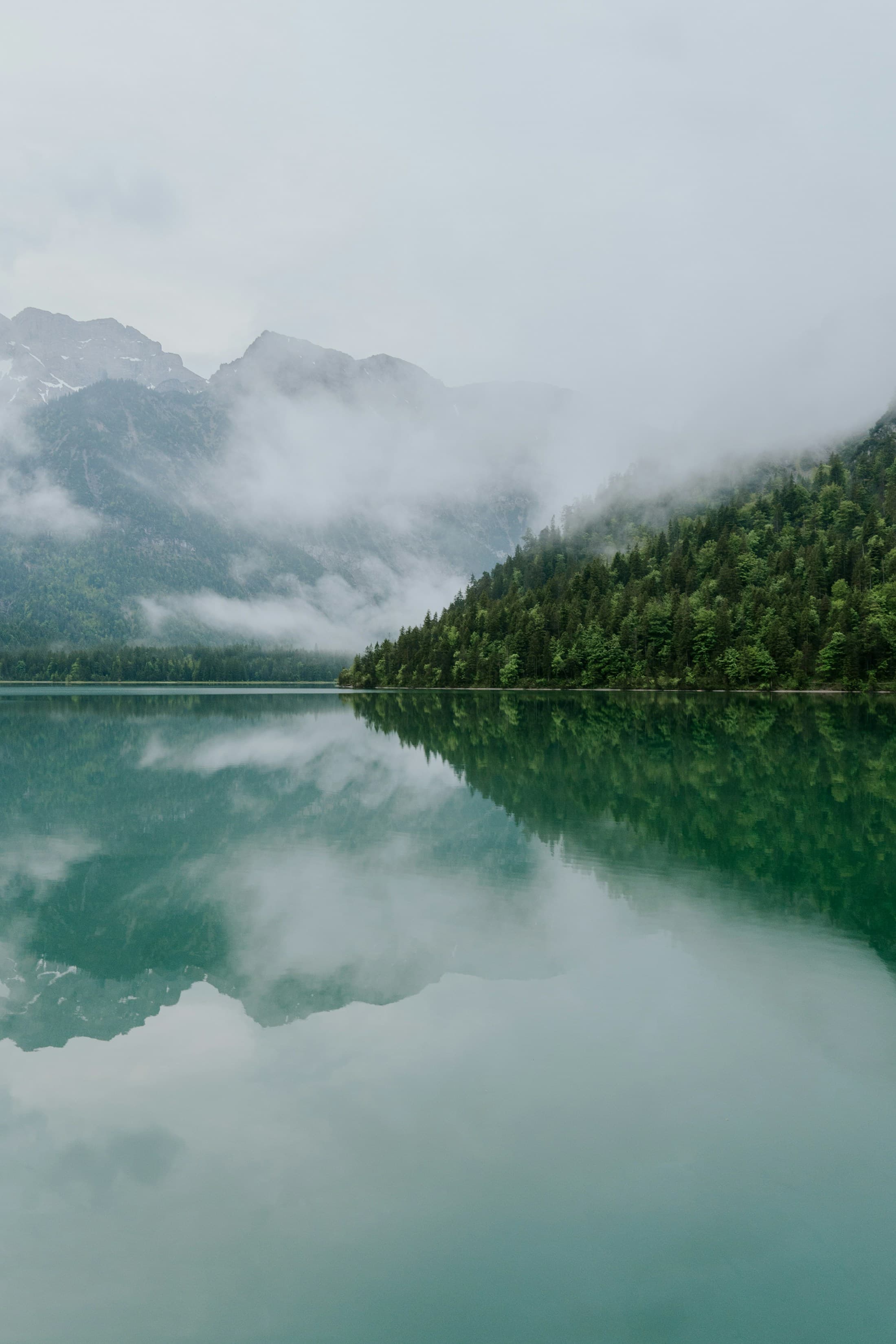 Un lac alpin et ses montagnes dans la brume